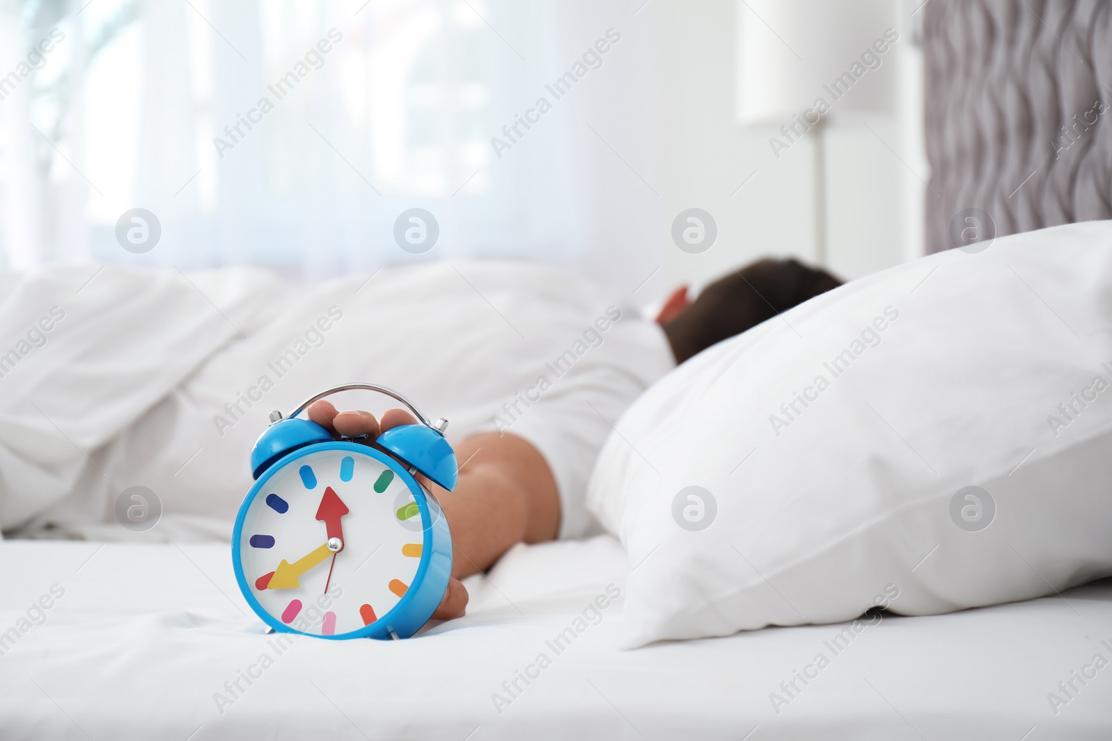 Photo of Man turning off alarm clock in bedroom