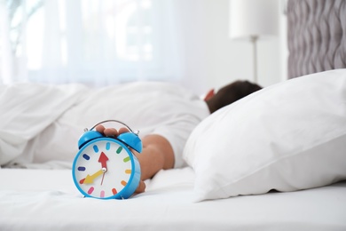 Man turning off alarm clock in bedroom