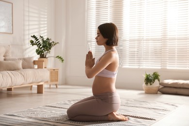 Photo of Young pregnant woman practicing yoga at home