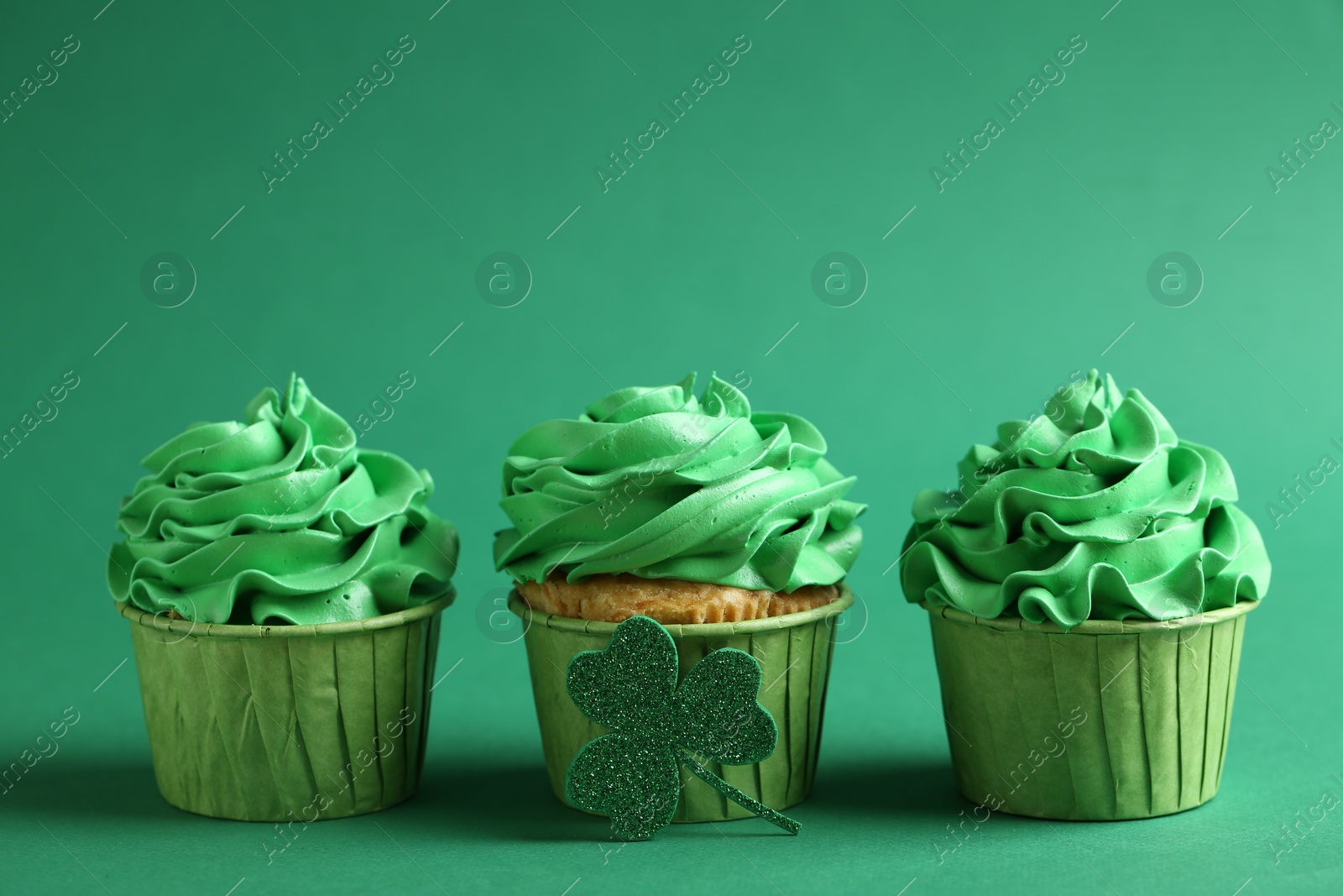 Photo of St. Patrick's day party. Tasty cupcakes on green background