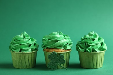 St. Patrick's day party. Tasty cupcakes on green background