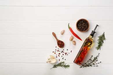 Photo of Cooking oil with different spices and herbs in bottle on white wooden table, flat lay. Space for text