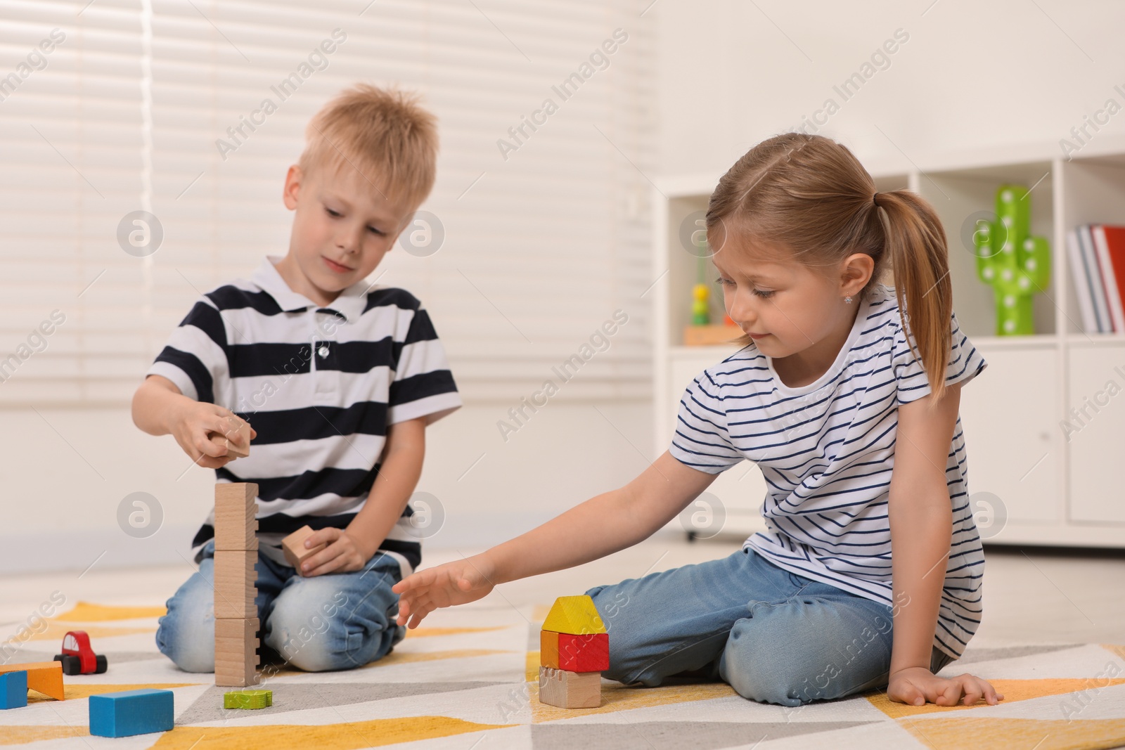 Photo of Little children playing with building blocks indoors. Wooden toys