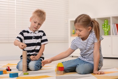Little children playing with building blocks indoors. Wooden toys