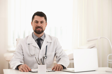 Portrait of male doctor in white coat at workplace