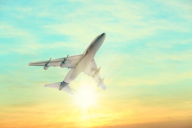 Image of Airplane flying in sky at sunrise. Air transportation