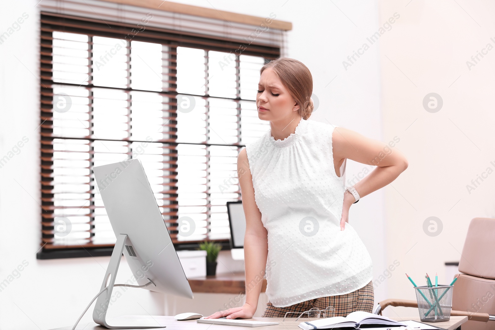 Photo of Young pregnant woman suffering from pain while working in office