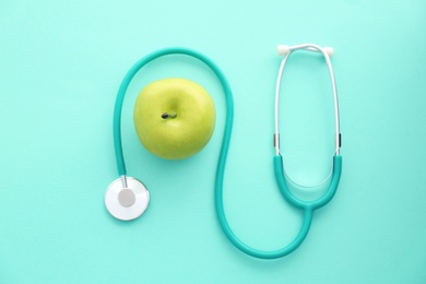 Photo of Flat lay composition with stethoscope and apple on color background