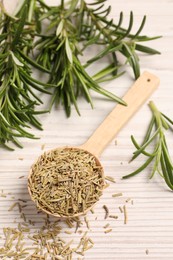 Photo of Spoon with dry rosemary and fresh twigs on white wooden table, above view