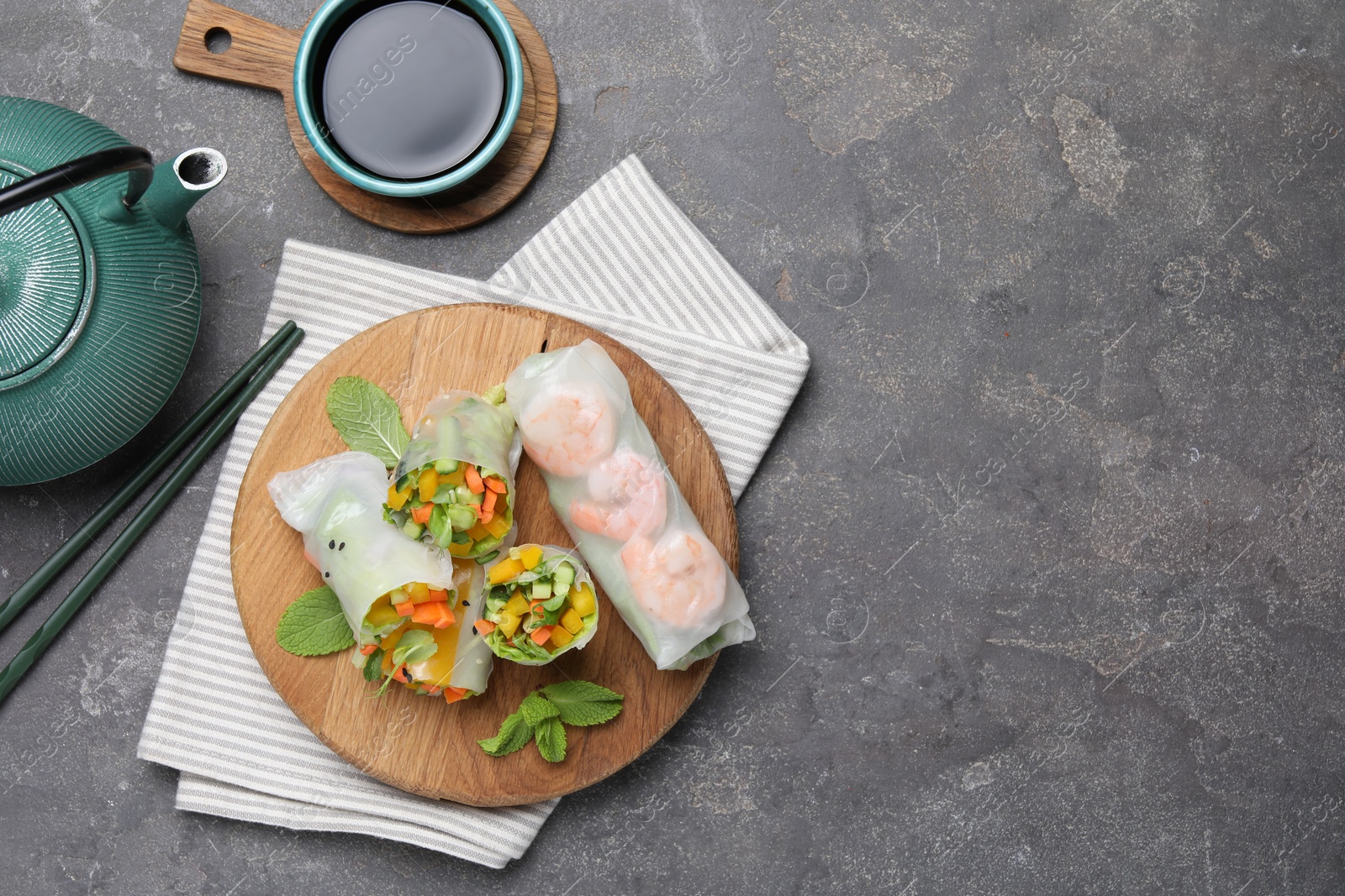 Photo of Tasty spring rolls served on grey textured table, flat lay. Space for text