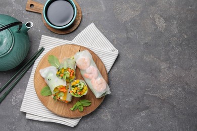 Photo of Tasty spring rolls served on grey textured table, flat lay. Space for text