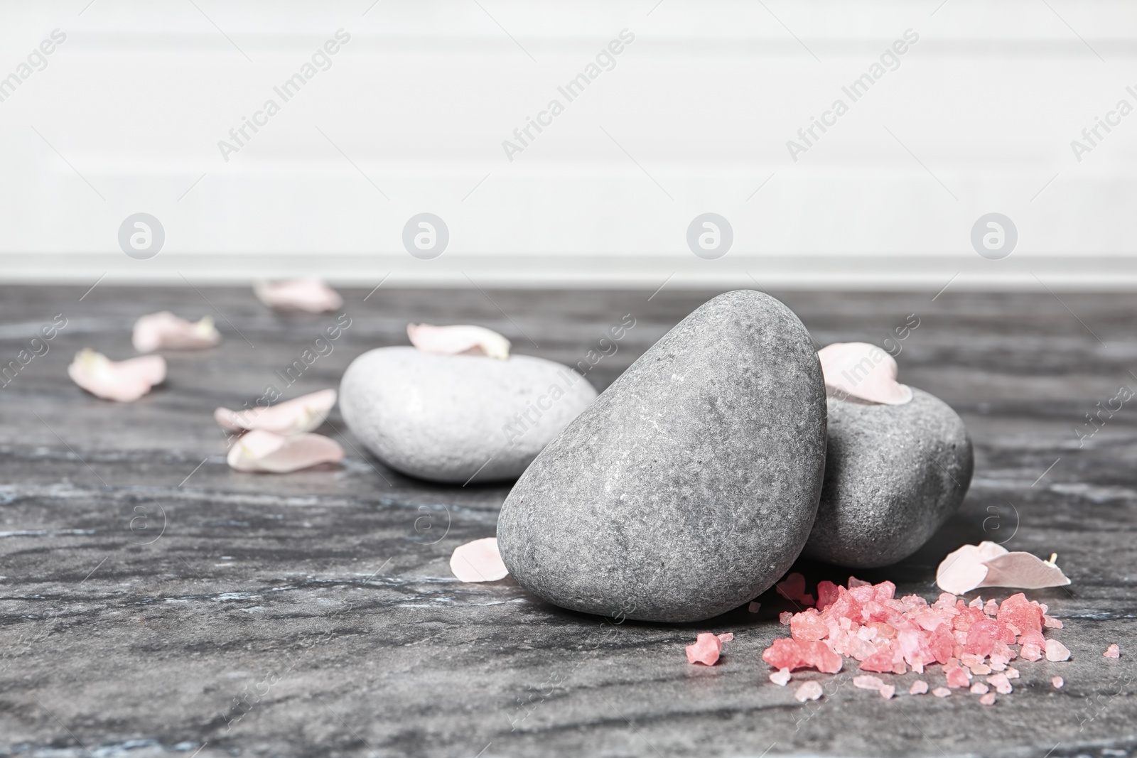Photo of Spa stones, sea salt and flower petals on marble table