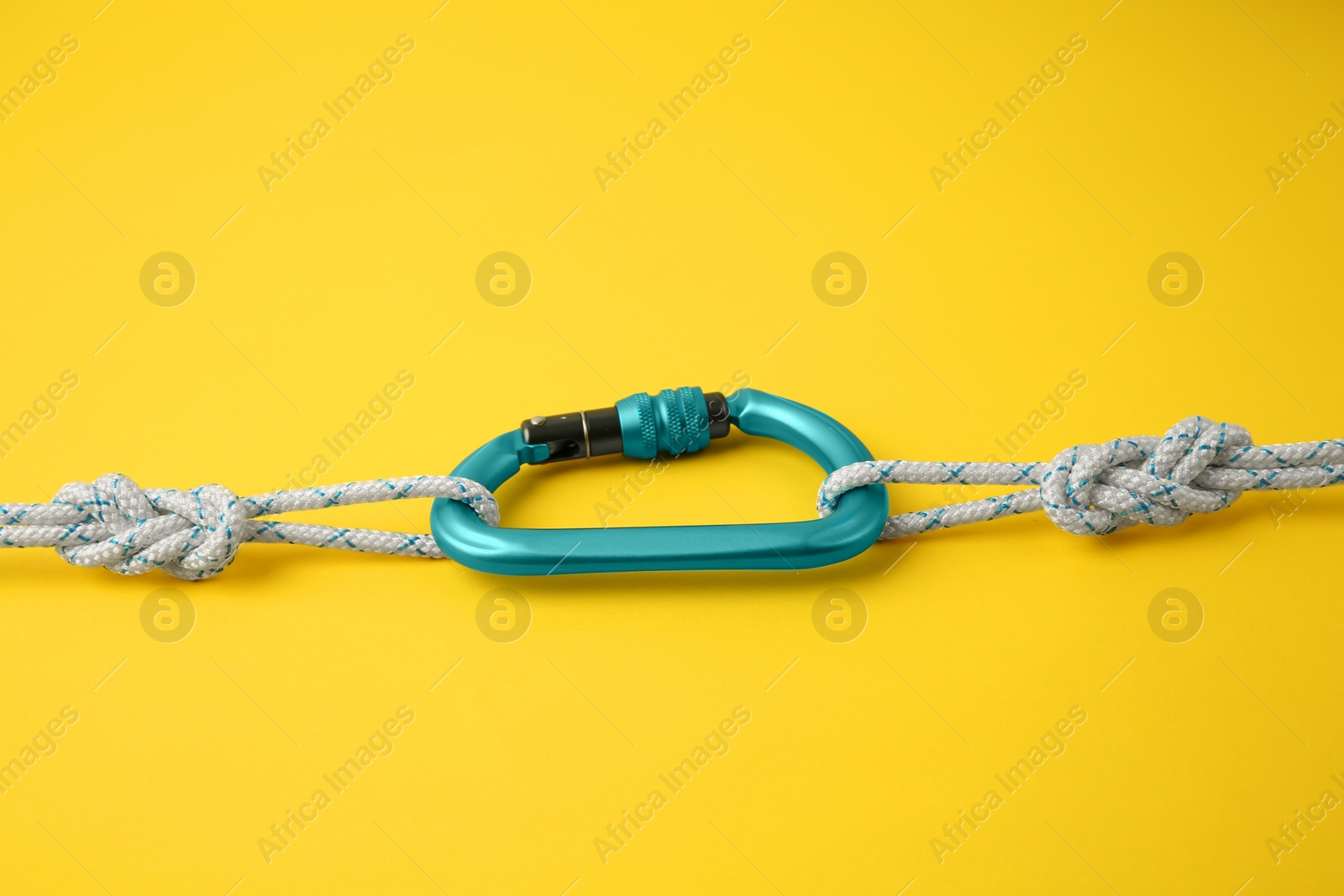 Photo of One metal carabiner with ropes on yellow background