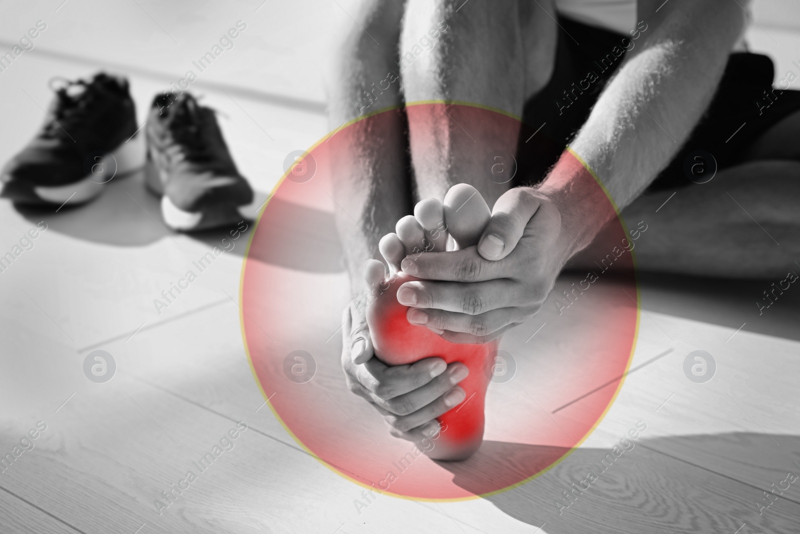 Image of Man suffering from foot pain on floor indoors, closeup