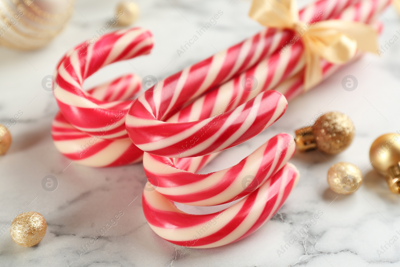 Photo of Bunch of Christmas candy canes on white marble table, closeup