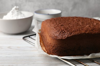 Homemade chocolate sponge cake on white wooden table, closeup. Space for text