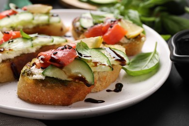Photo of Delicious bruschettas with balsamic vinegar and toppings on black table, closeup