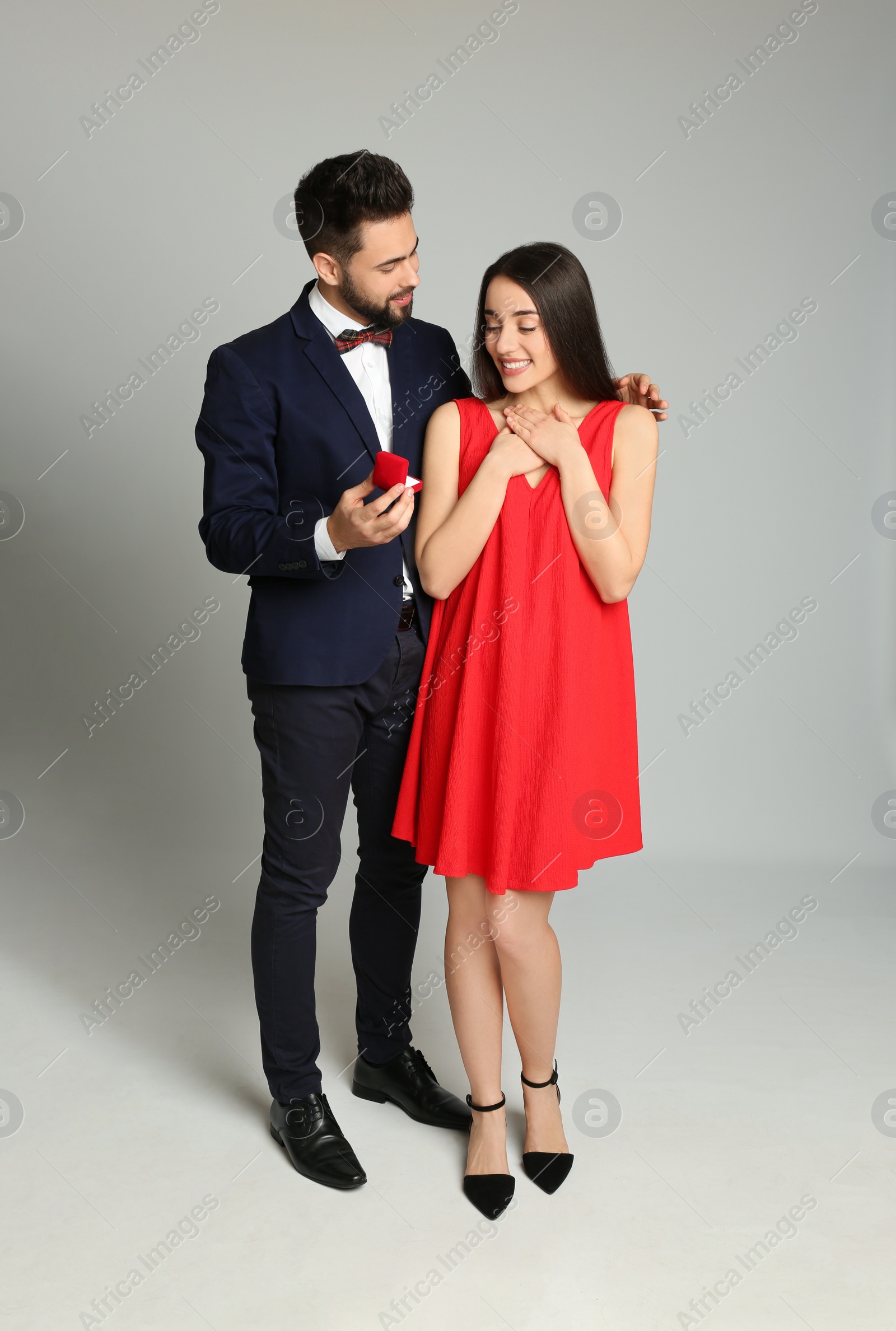 Photo of Man with engagement ring making marriage proposal to girlfriend on light grey background