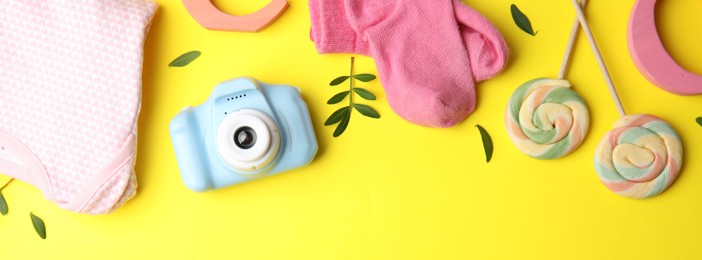 Photo of Flat lay composition with toy camera on yellow background, space for text. Future photographer