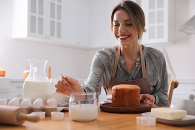Photo of Young woman making traditional Easter cake in kitchen