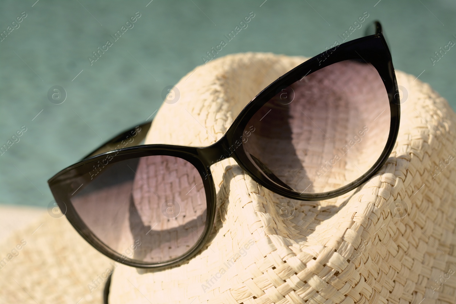 Photo of Stylish hat and sunglasses on blurred background, closeup