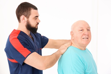 Young physiotherapist working with senior patient in clinic