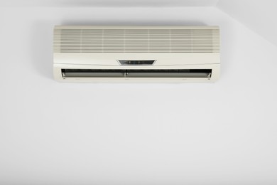 Photo of Modern air conditioner on white wall indoors