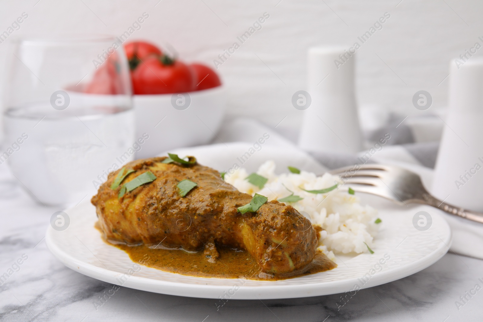 Photo of Delicious rice and chicken with curry sauce served on white marble table, closeup