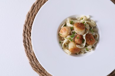 Photo of Delicious scallop pasta with spices in bowl on white table, top view