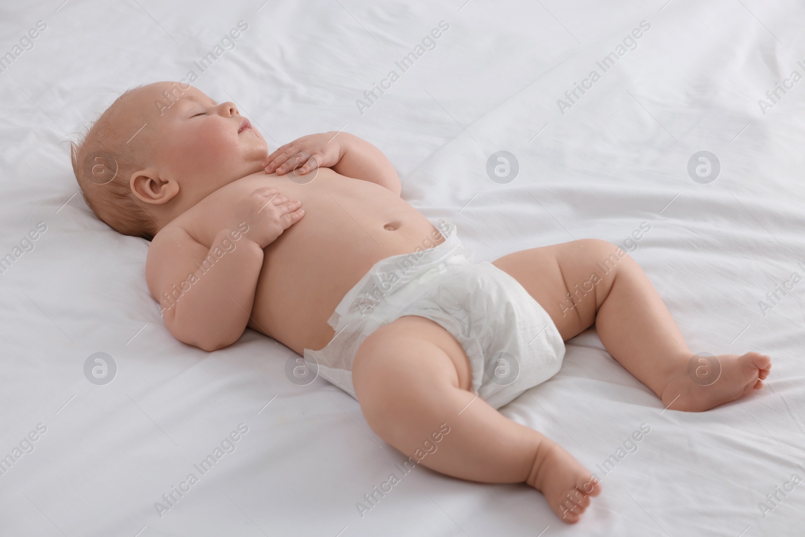 Photo of Cute newborn baby in diaper sleeping on bed at home