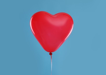 Photo of Festive heart shaped balloon on light blue background