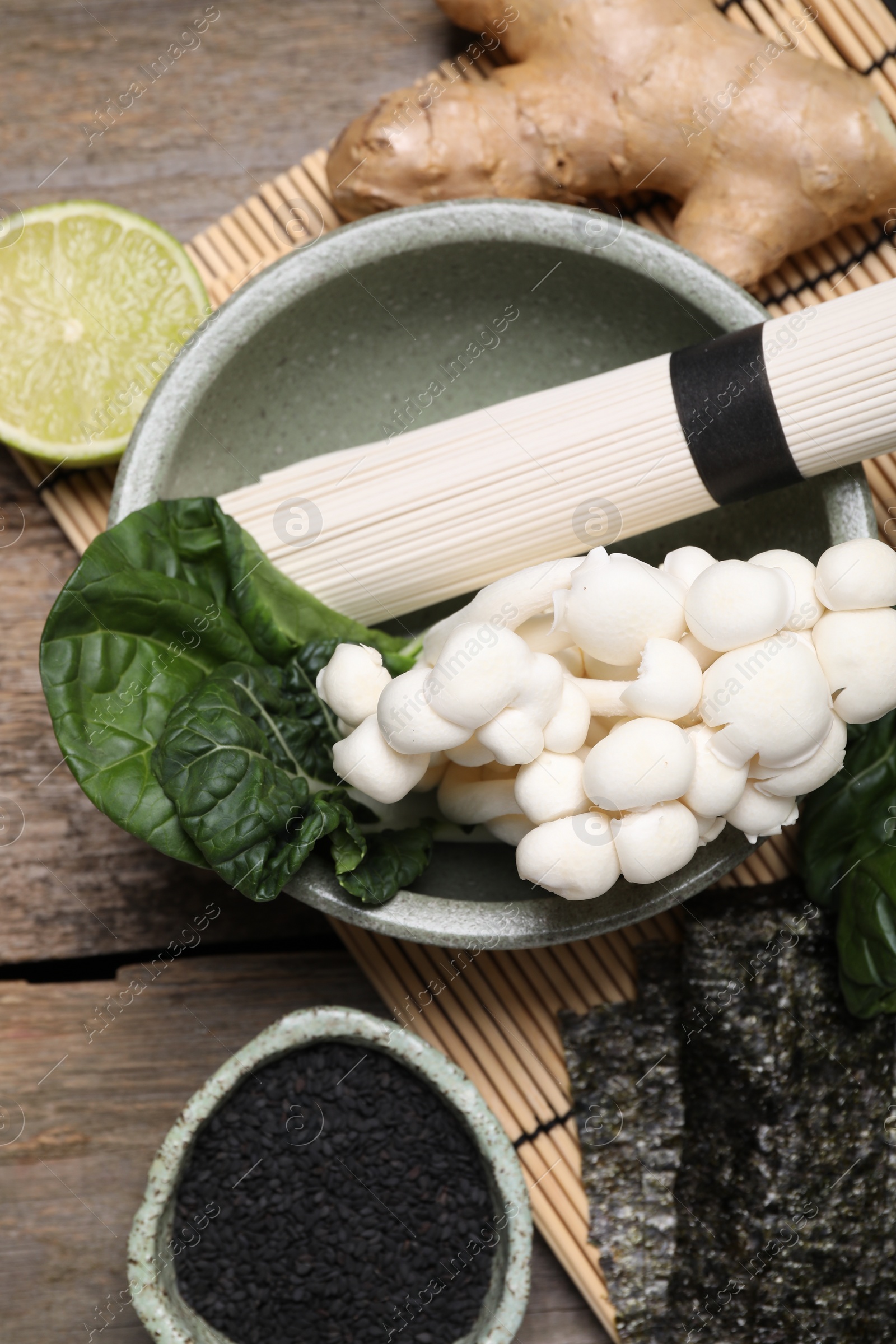 Photo of Cooking delicious ramen soup. Different ingredients on wooden table, flat lay