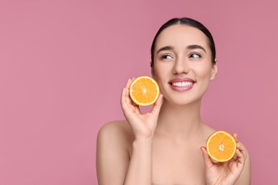 Photo of Beautiful young woman with pieces of orange on pink background. Space for text