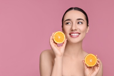 Beautiful young woman with pieces of orange on pink background. Space for text