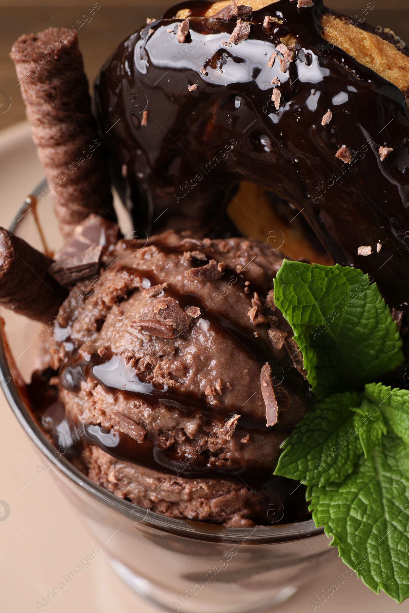 Photo of Delicious chocolate ice cream with wafer sticks, donut and mint in glass dessert bowl on table, above view