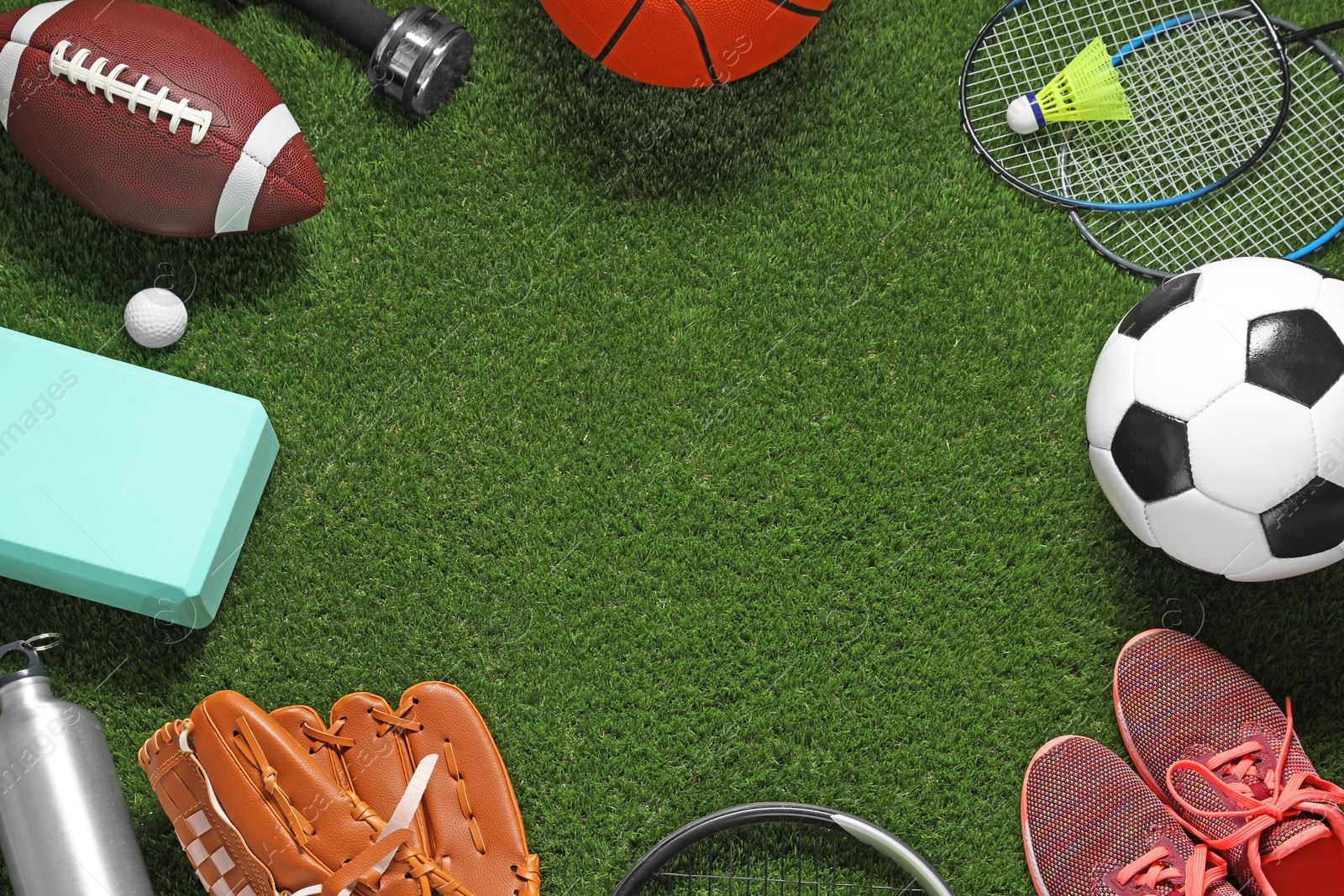 Photo of Frame made of different sports equipment on green grass, flat lay. Space for text