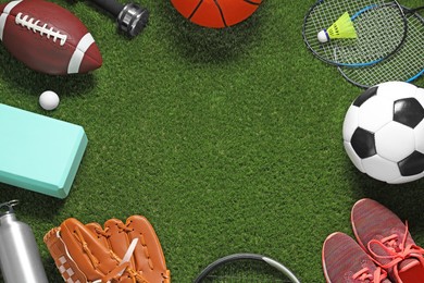 Photo of Frame madedifferent sports equipment on green grass, flat lay. Space for text