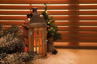 Beautiful decorative Christmas lantern with burning candle on window sill. Space for text