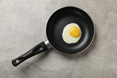Photo of Delicious fried egg in frying pan on grey table, top view