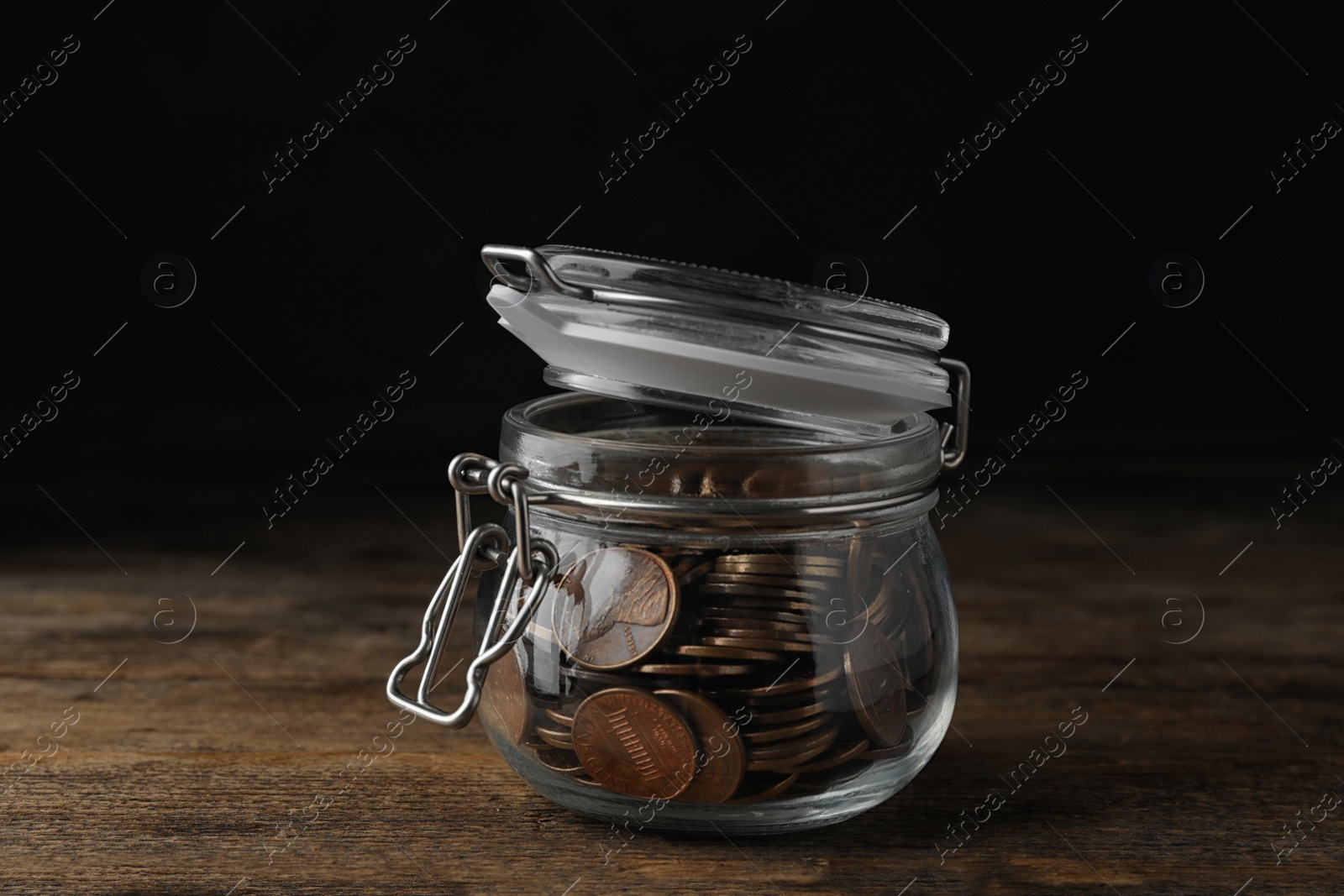 Photo of Glass jar with coins on wooden table