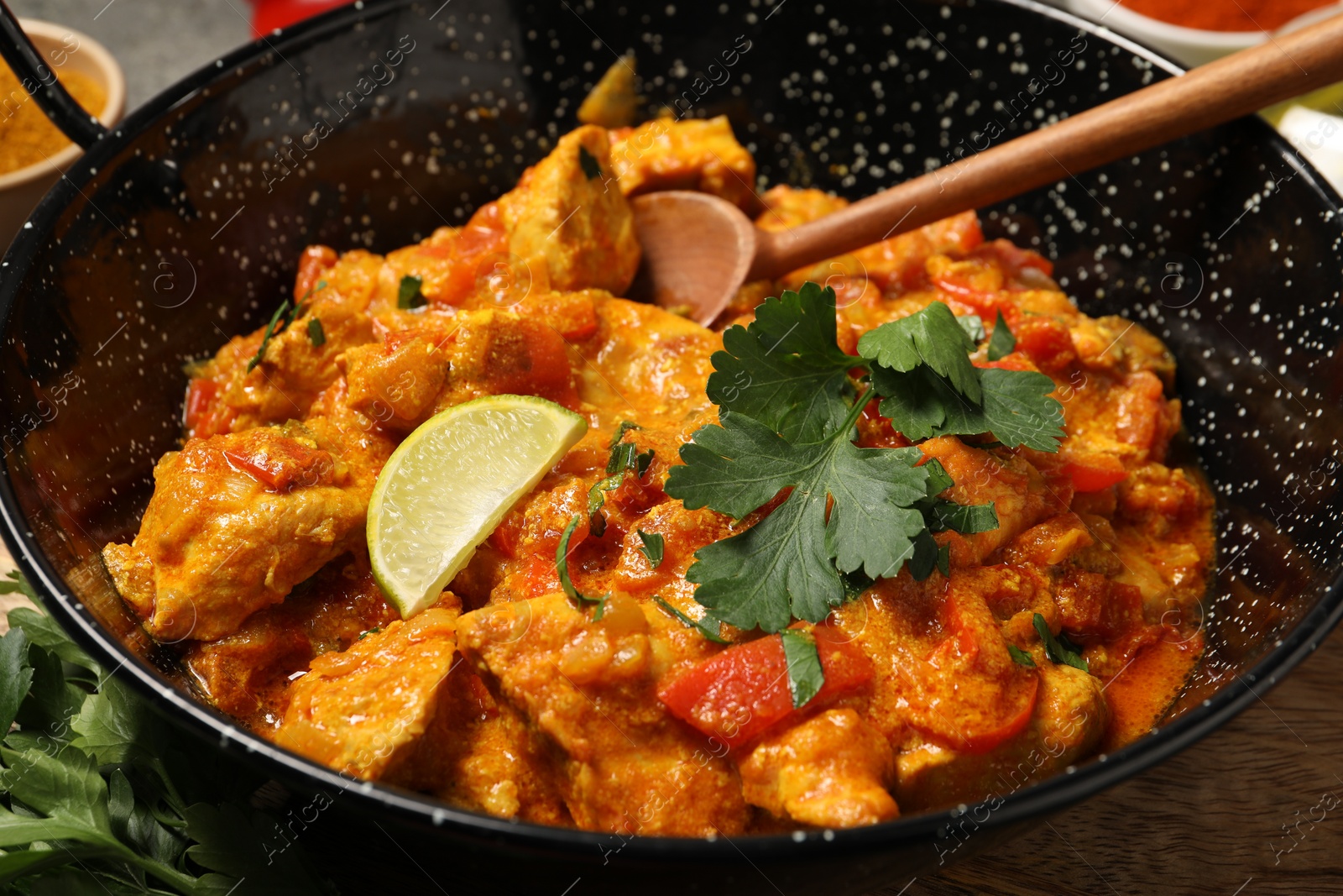 Photo of Delicious chicken curry in frying pan on table, closeup