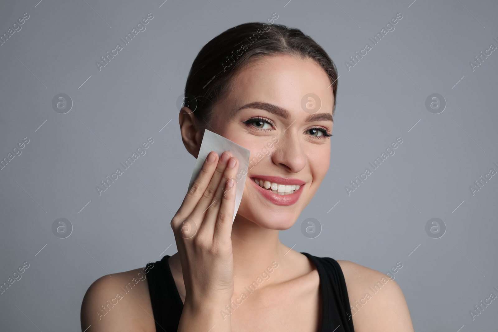 Photo of Beautiful woman using mattifying wipe on grey background