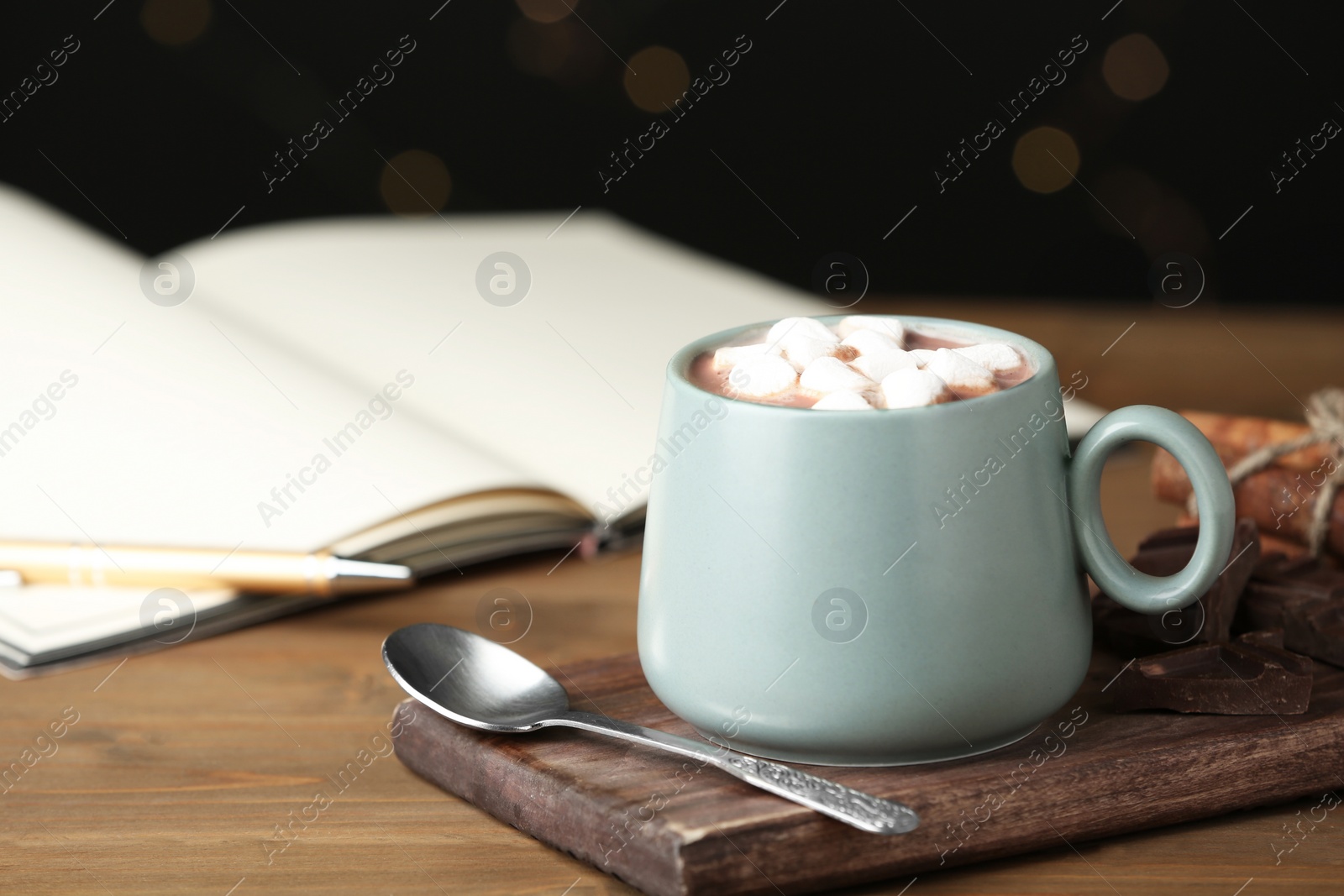 Photo of Delicious cocoa drink with marshmallows in cup on wooden table