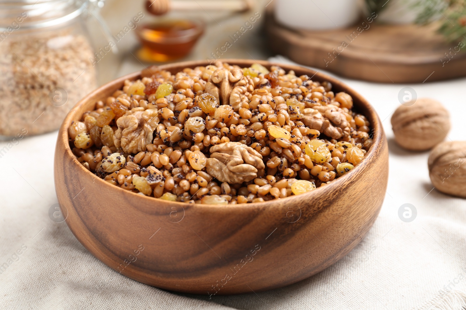 Photo of Fresh tasty traditional kutia in wooden bowl on light towel, closeup