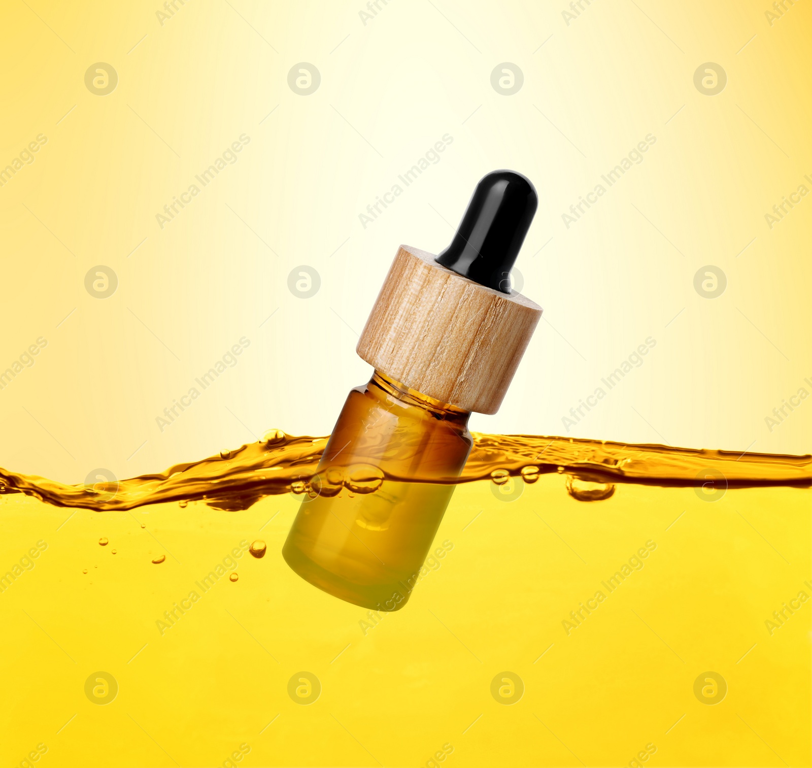 Image of Bottle of cosmetic product floating in essential oil against gold gradient background