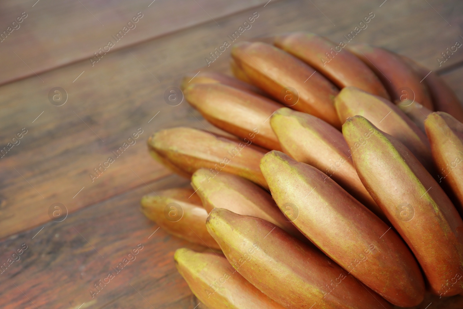 Photo of Tasty purple bananas on wooden table, closeup. Space for text