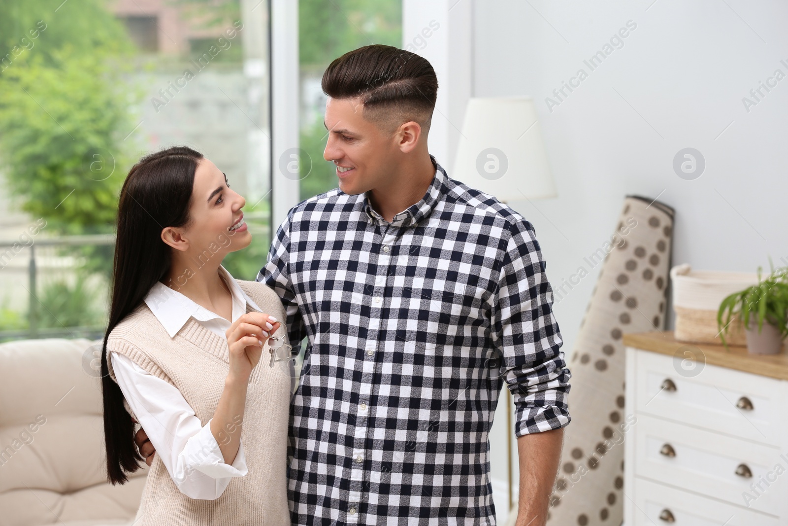 Photo of Happy couple with key from their new house indoors