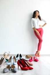 Young woman with many beautiful shoes indoors