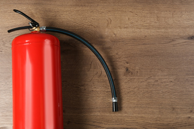Fire extinguisher on wooden background, top view. Space for text