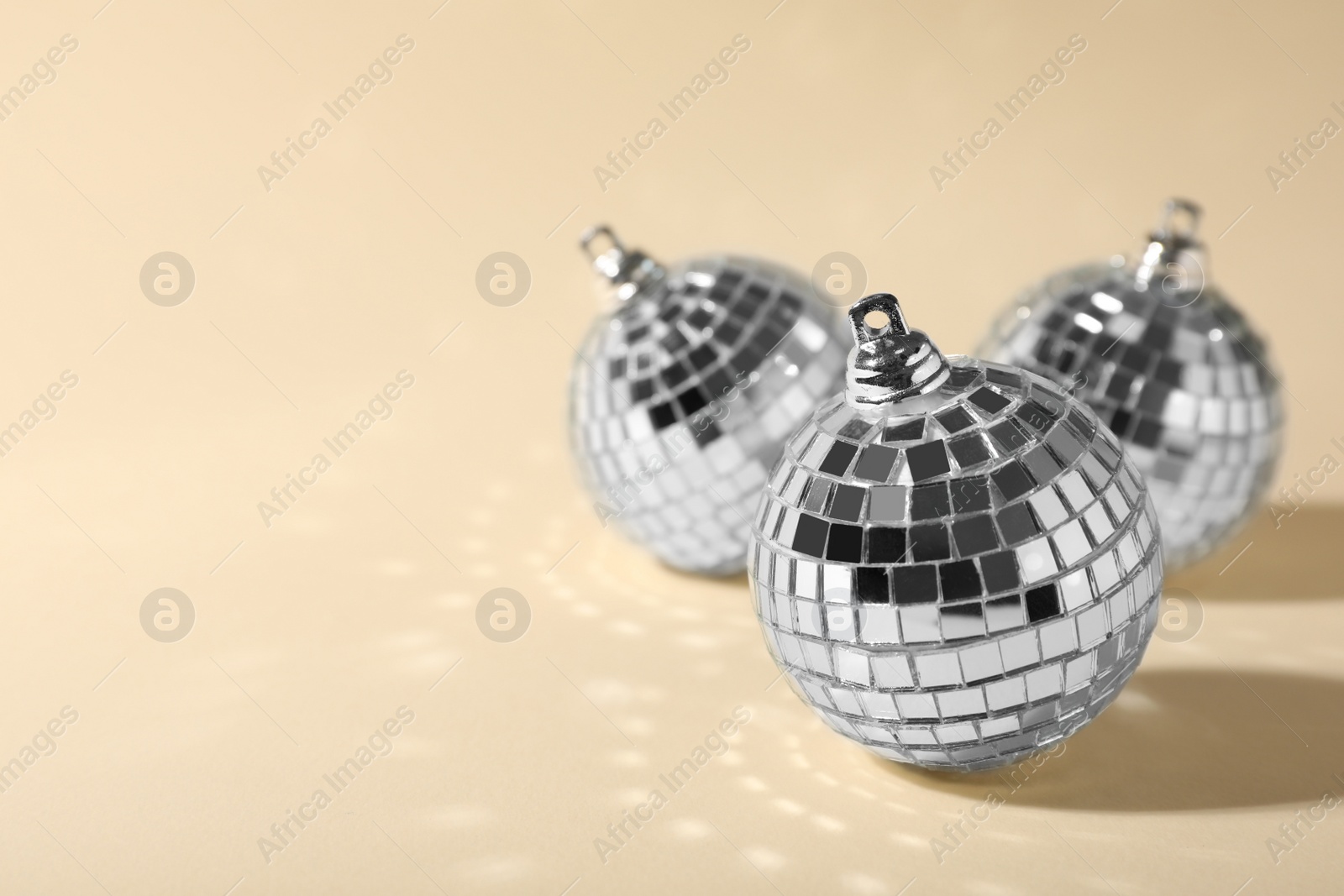 Photo of Shiny disco balls on beige background, space for text
